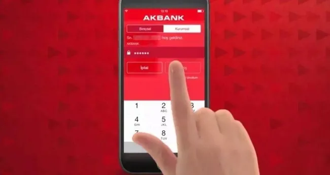 Close-up of a hand tapping the AKBANK mobile banking login screen on a red phone keypad, entering a PIN or password.
