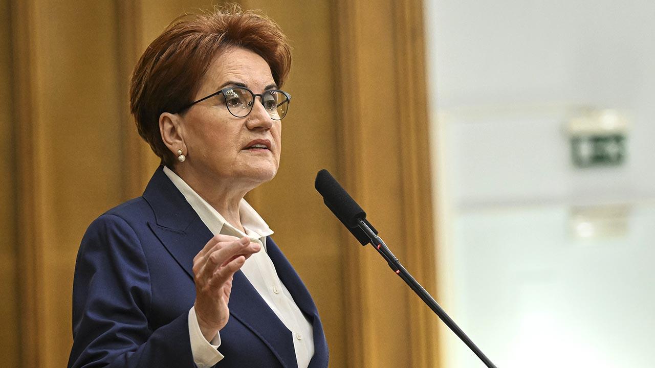 Woman in a navy blazer speaking at a podium with a microphone in front of her, gesturing with her hand.